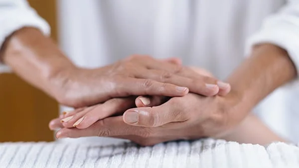 Close up image of a person in white clad performing a hand massage to another person