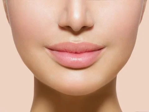 Close up of a womans lips where, the lips are plump and light pink coloured and the skin around the mouth is smooth